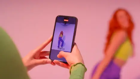 Studio Shot Of Woman Taking Photo Of Friend Dancing On Mobile Phone Against Pink Background 5