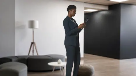 Businesswoman In Suit Messaging On Mobile Phone In Modern Open Plan Office