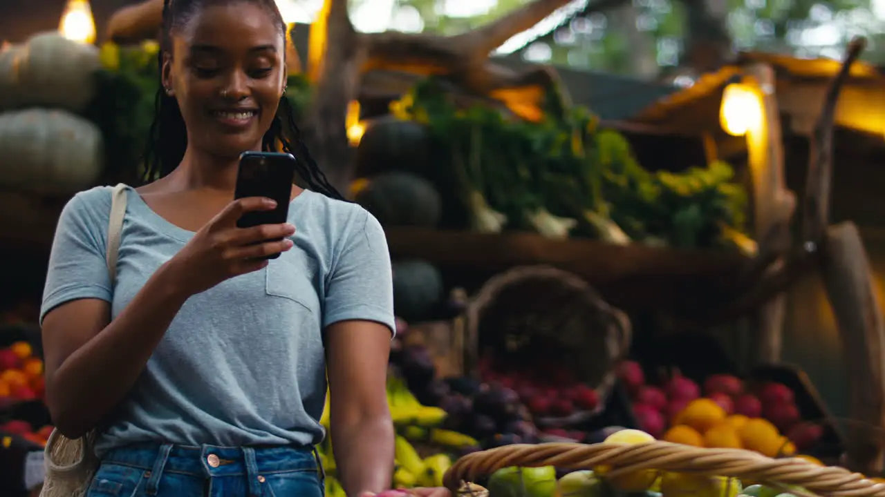 Female Customer At Market Stall Taking Photo Of Fresh Produce On Mobile Phone