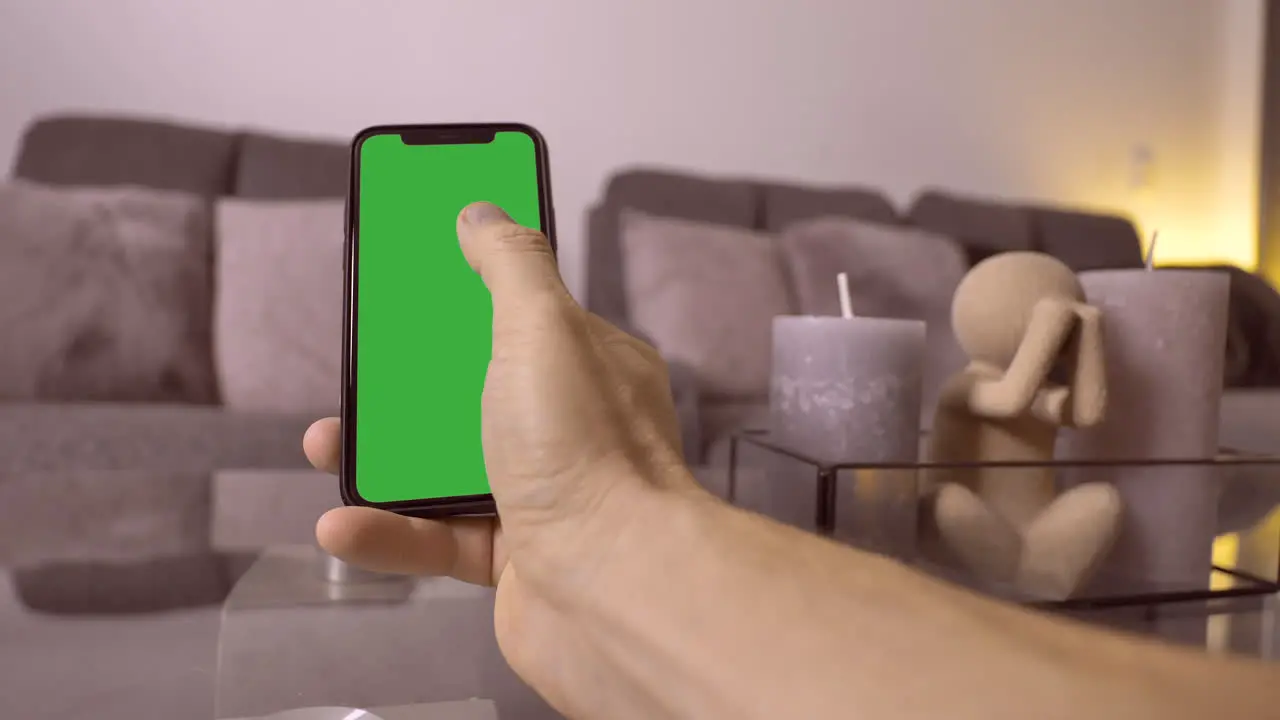 Male person swipes on mobile phone green screen at home in living room close up prores 4k resolution