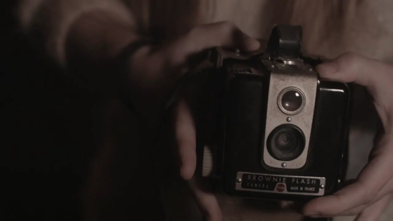 Girl's hands open Box Brownie camera case and reveals to camera outdoors low light