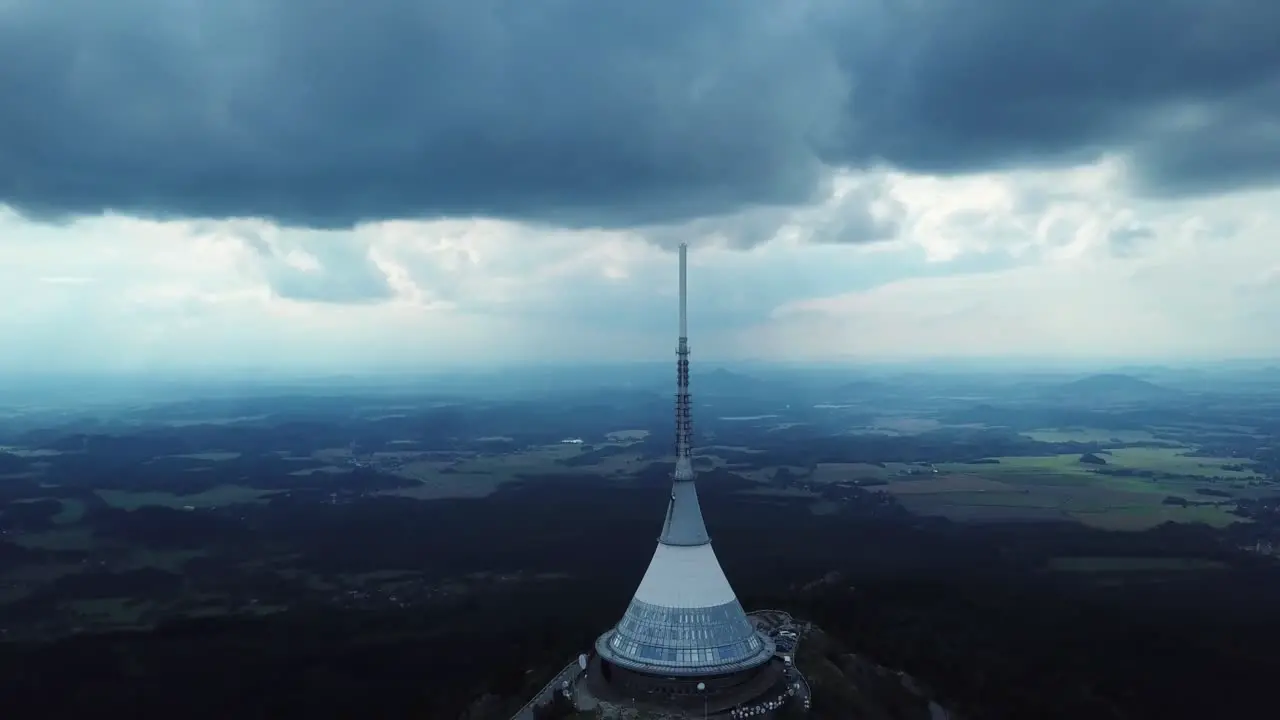 Jested tower during a part clouded day with Liberec town in the distance Drone orbiting descending and pan up 4k or UHD 30fps