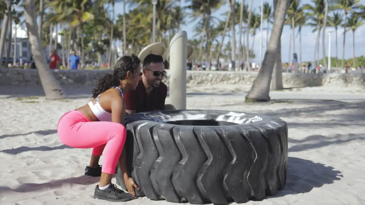 Sporty couple training with tyre together