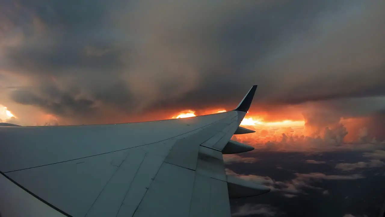 Airplane wing with thick clouds and sunset