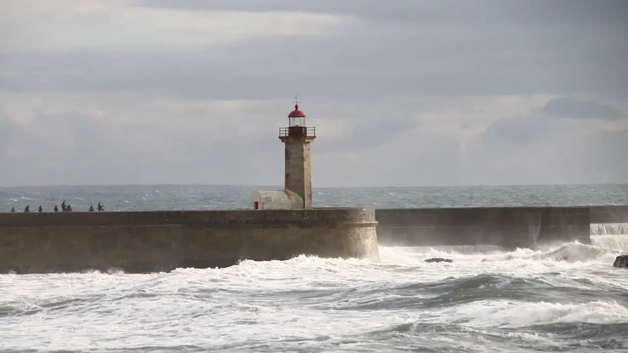 Waves crushing lighthouse in Porto in a cloudy and windy evening