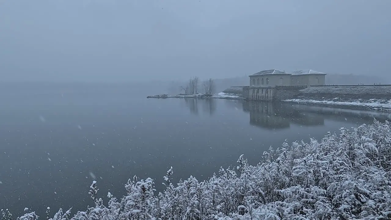 Heavy snowfall over a beautiful reservoir and nearby causeway dam