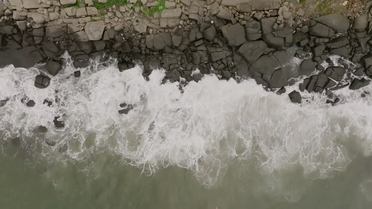 Static slow motion aerial footage top down of ocean waves crashing into rocks