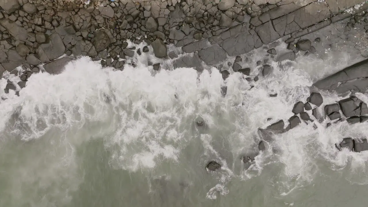 Aerial footage top down of ocean waves crashing into rocks