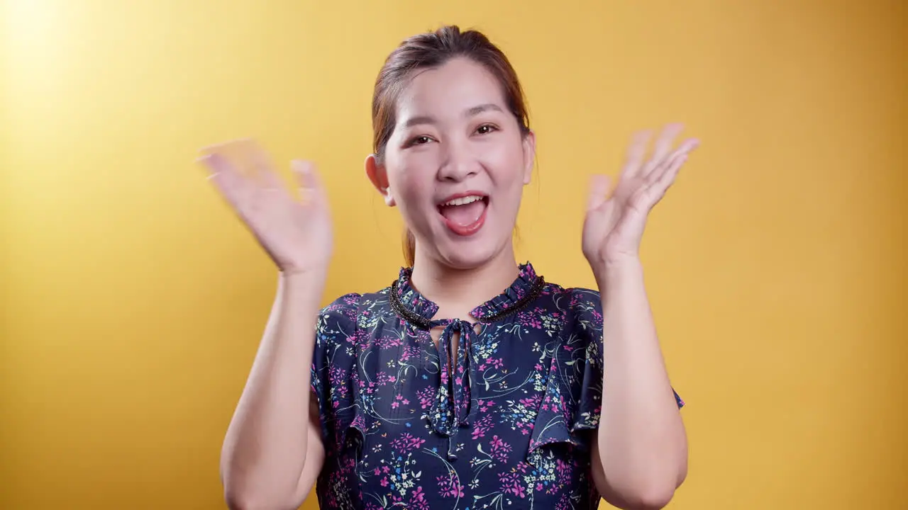 Kind friendly Asian woman charmingly smiles waving her hand in a happy greeting welcome or goodbye