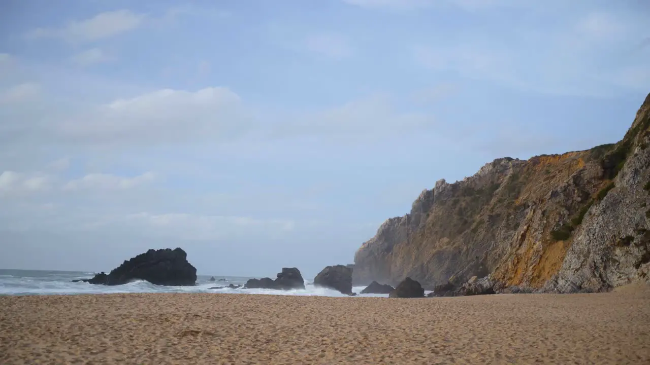 Sea waves crashing at a hilly beach of Praia da Adraga in Portugal