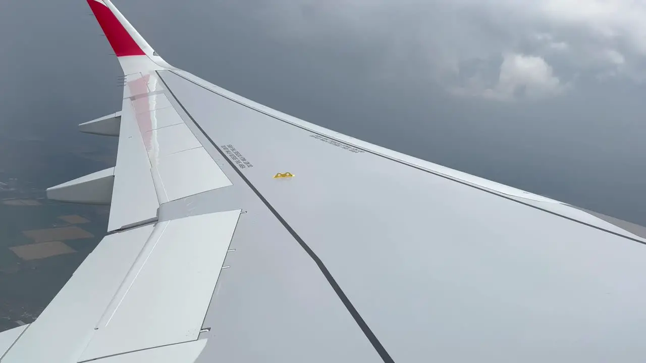 Left wing view of a jet plane while crossing a thunderstorm with rain daylight