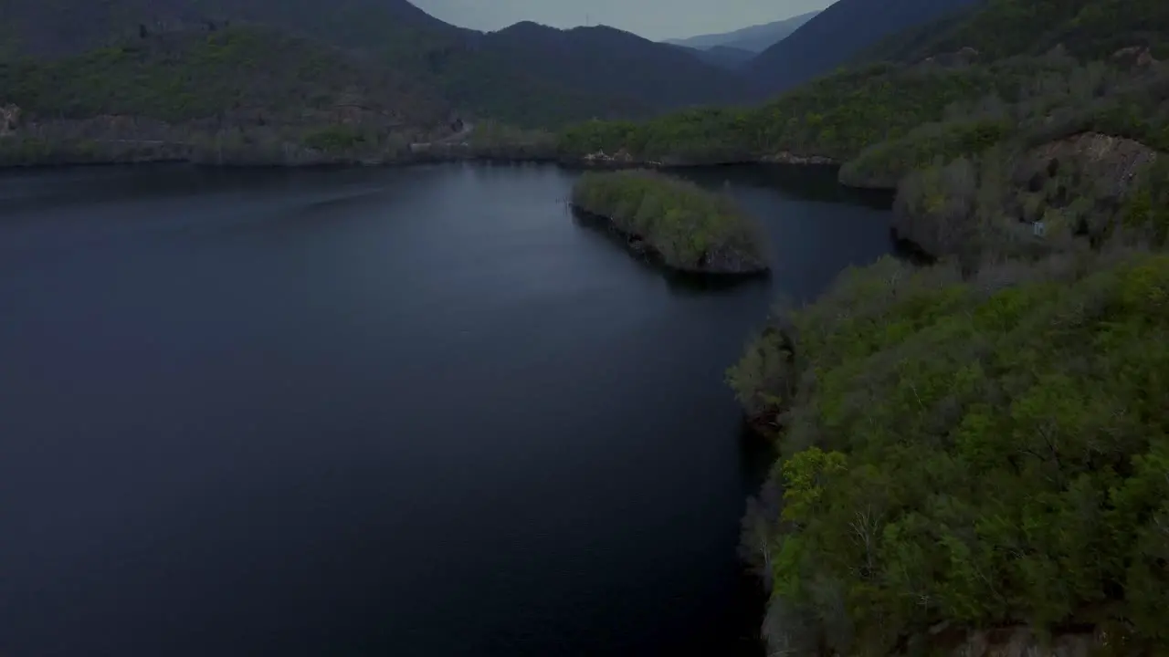 Aerial establishing shot of dark lake and forest during a stormy winter day