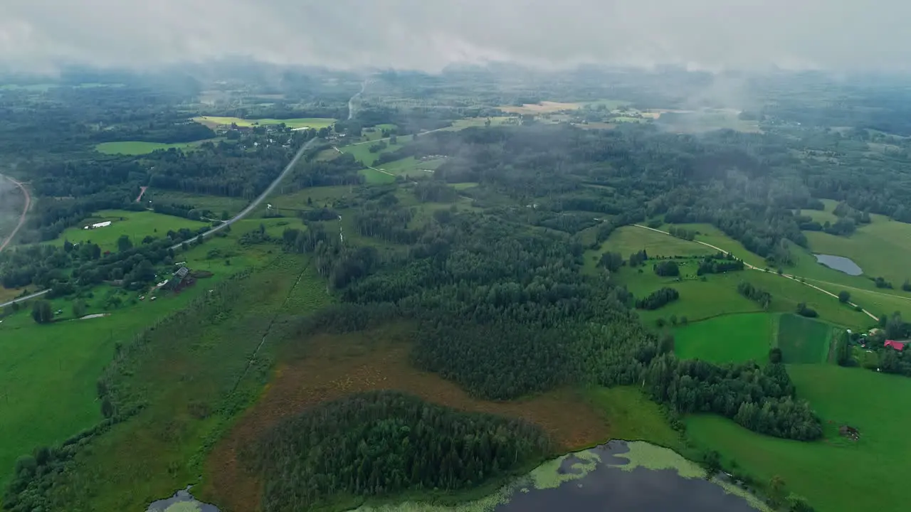 Aerial above the clouds and a beautiful green landscape with grassland and trees