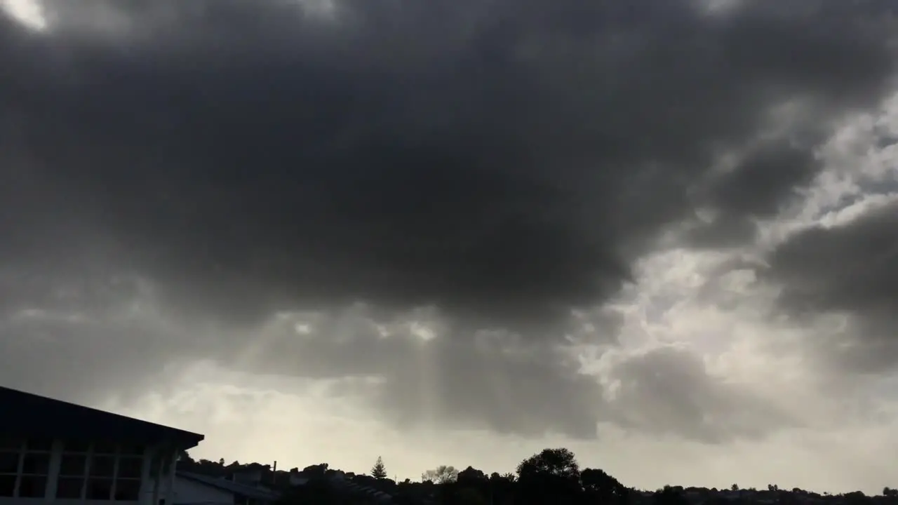 Dark grey ominous clouds with sun rays beaming through over the cityscape