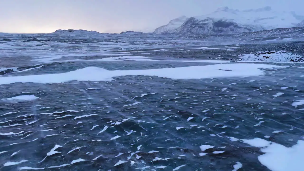 Snow blown across an Icelandic Glacier as the sun sets over horizon 4K