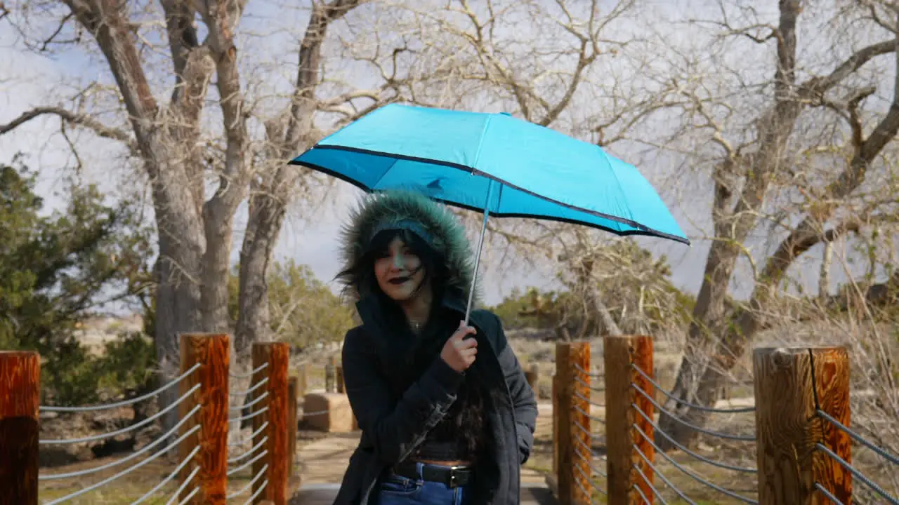 A beautiful woman opening a blue umbrella and smiling happily during a rain storm to protect from bad weather SLOW MOTION