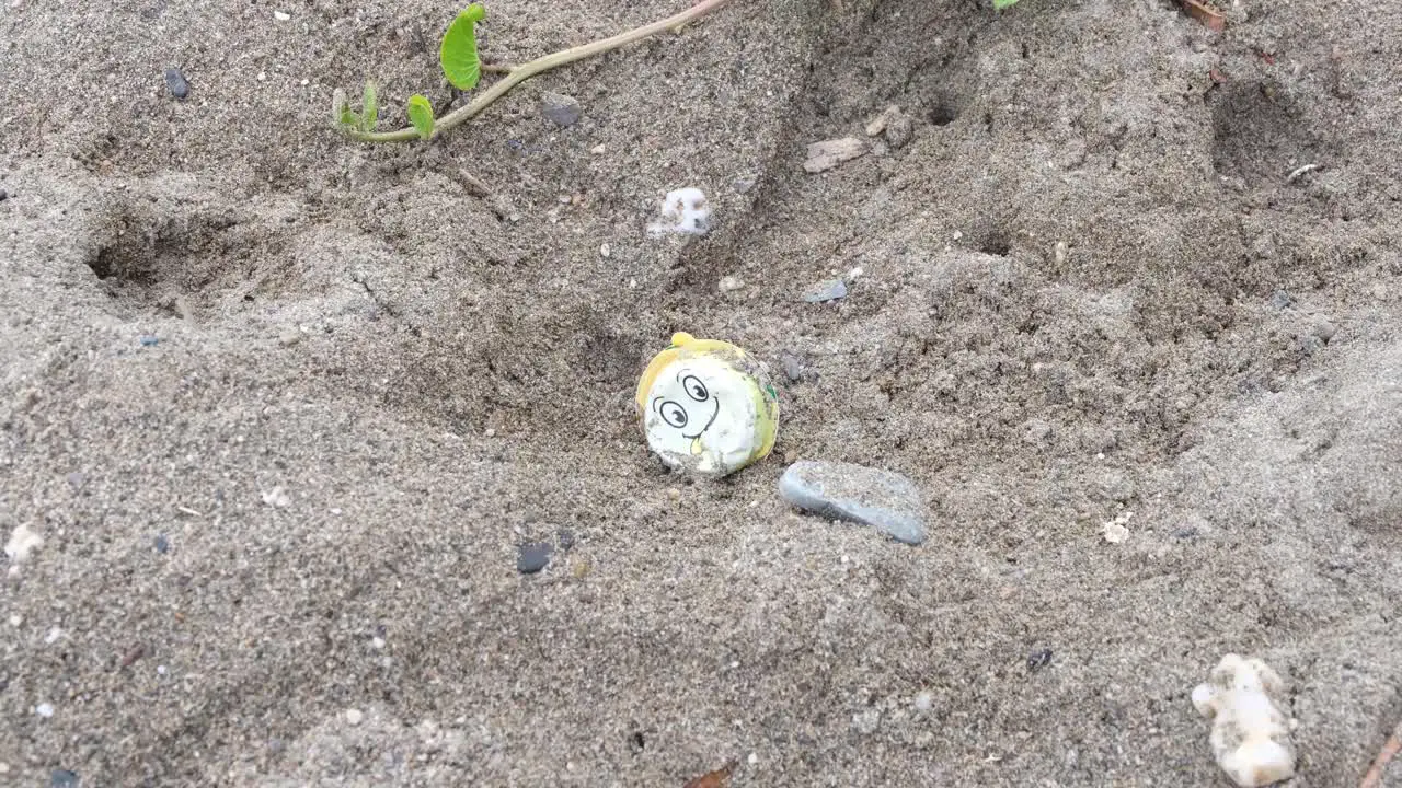 Discarded plastic toy waste with a happy smiley face washed onto beach from ocean negative environmental and marine impact