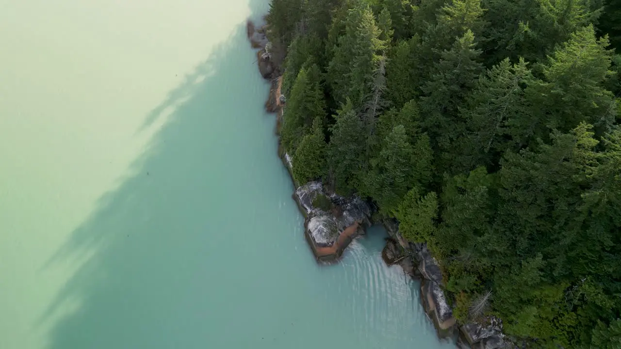 Aerial topdown pan of Howe Sound ocean coastline and trees Stawamus Chief reveal Squamish BC Canada