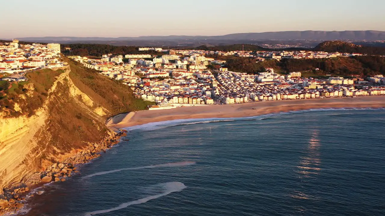 Town of Nazare Portugal during sunset golden hour Aerial pan right reveal