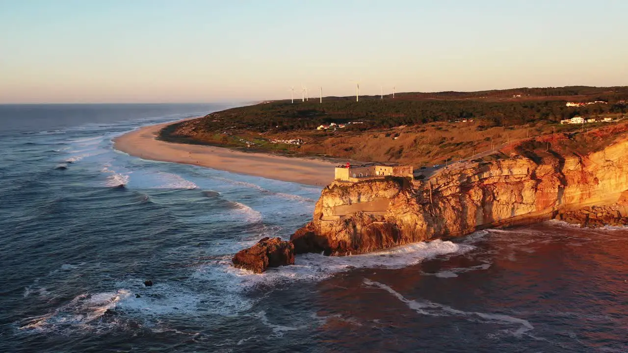 Nazare Portugal lighthouse near Praia do Norte during sunset Aerial circle pan