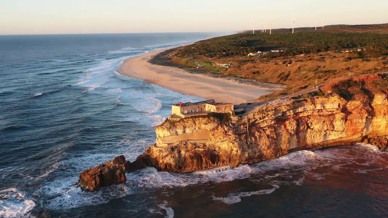 Lighthouse in Nazare Portugal near Praia do Norte during sunset Aerial circle out shot