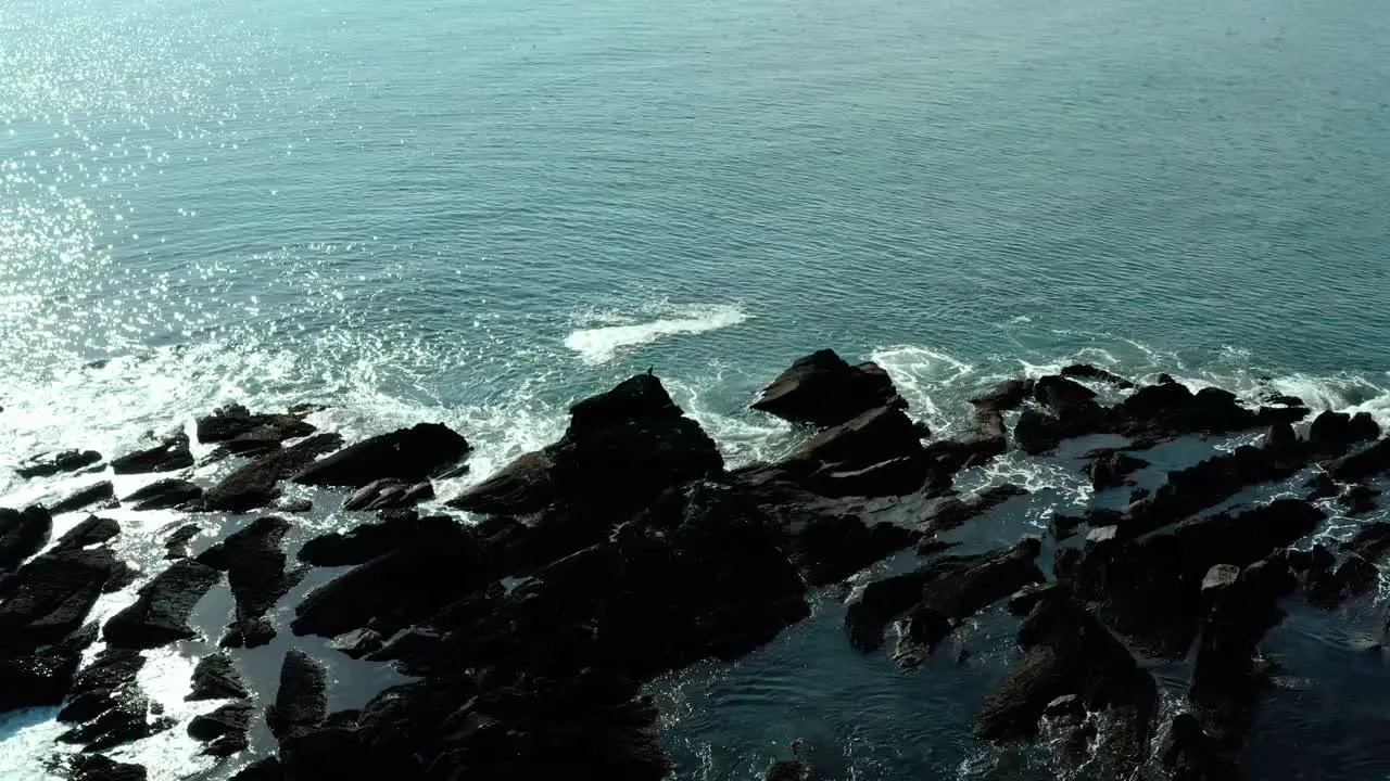 birds eye view of ocean waves near rocks at ocean in summer at day