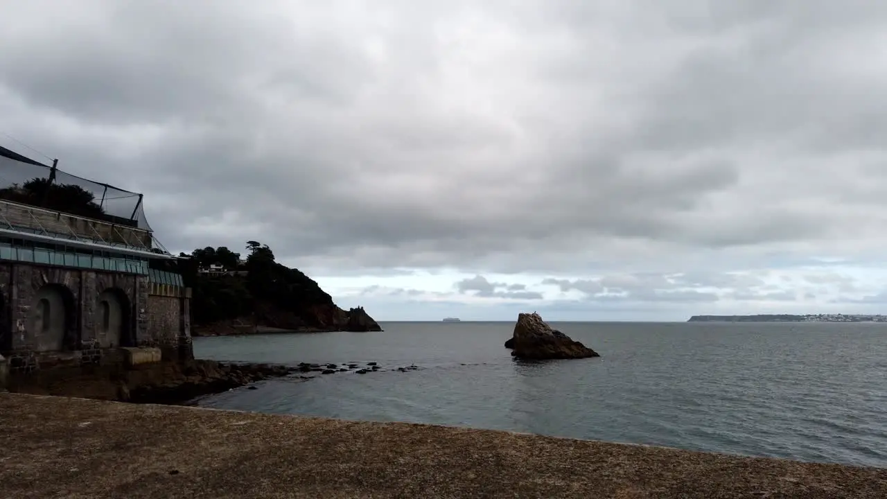 Time lapse shot showing ocean shore and moving dark clouds in Torquay South Devon