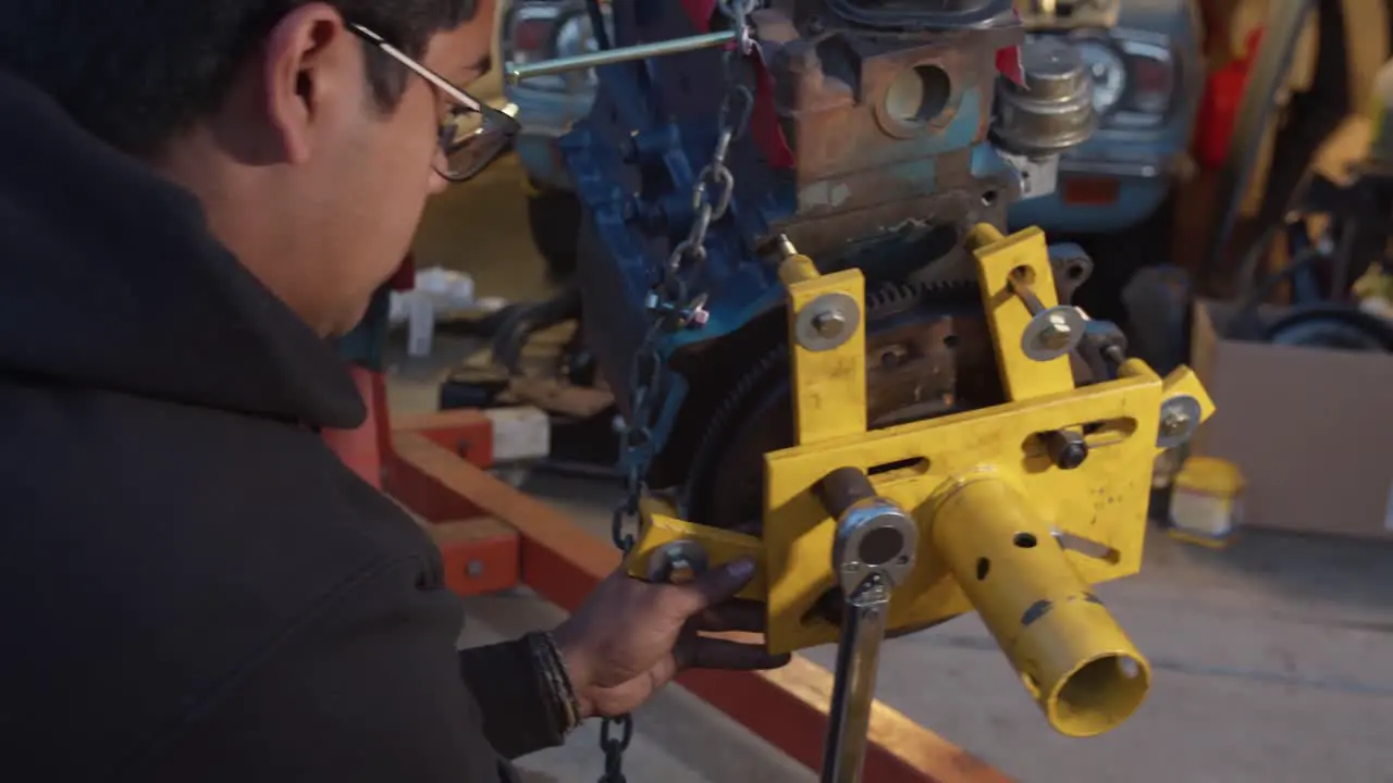 Young mechanic wrenching engine stand bracket to engine