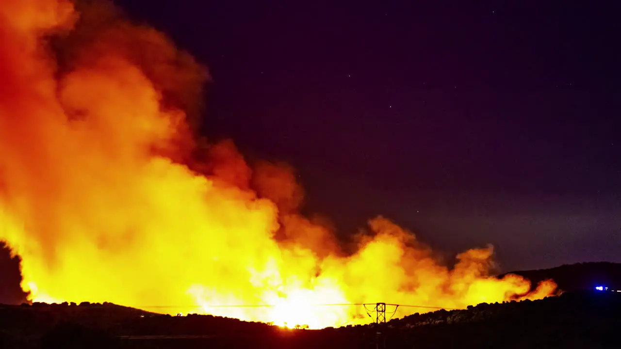 Very large forest fire with high rising flames near a power line