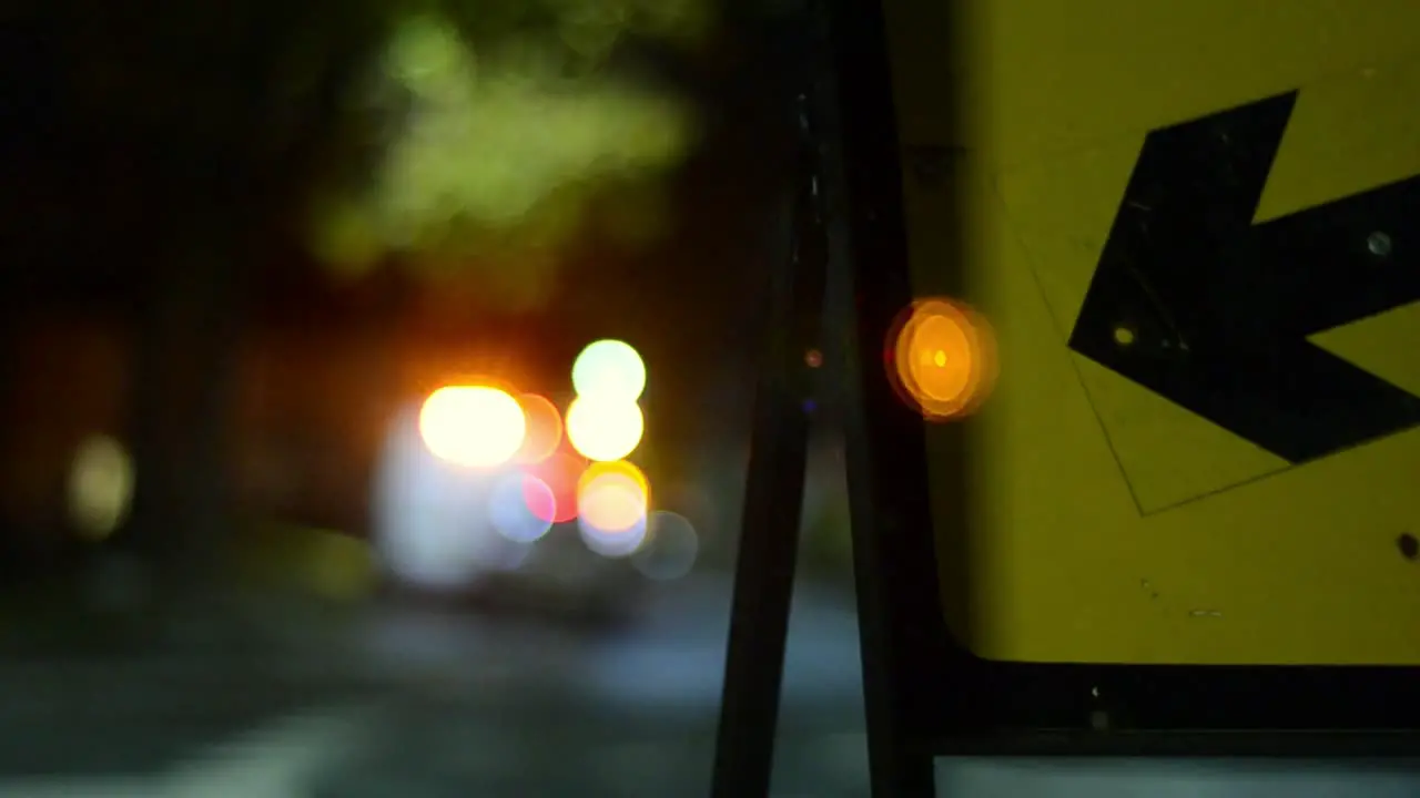 Night time road traffic sign pointing direction with traffic bokeh