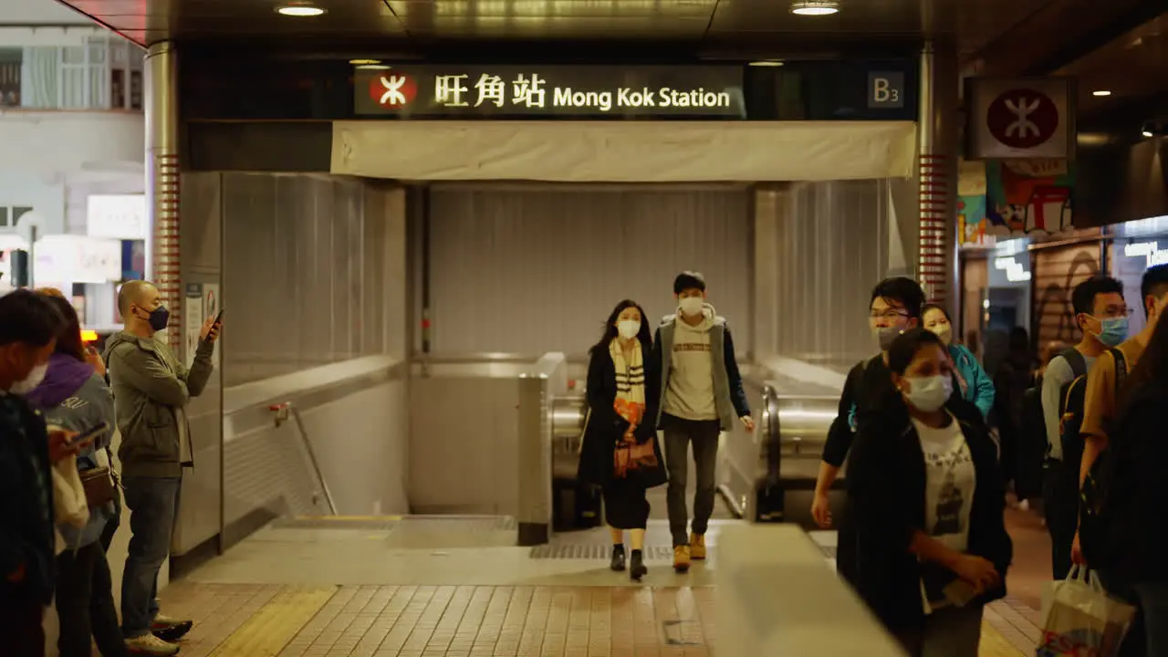 People walking outside of the Mong Kok Station at night in Hong Kong