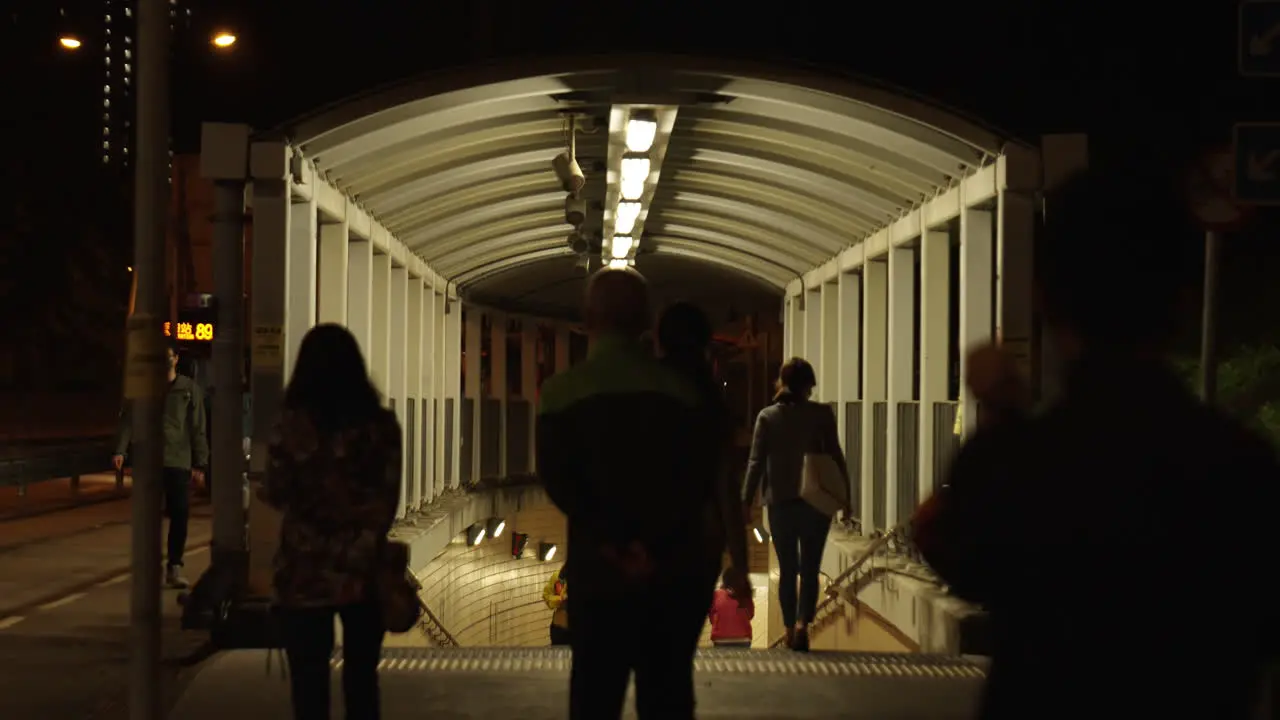 Static shot of people walking at night into the Hong Kong subway