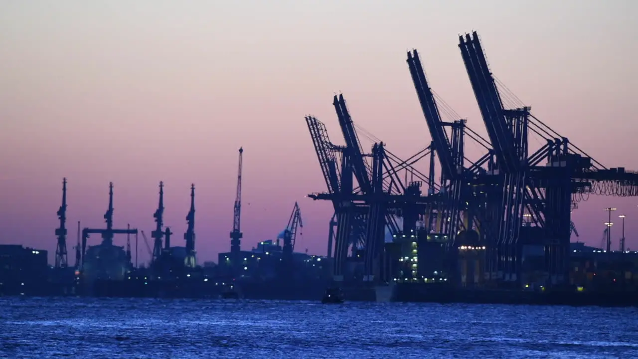 Cranes of container terminal in the port of Hamburg morning light before sunrise blue hour economy market