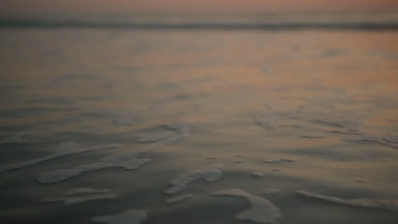 Small and calm bubble waves washing over the sand and gently breaking against the shore