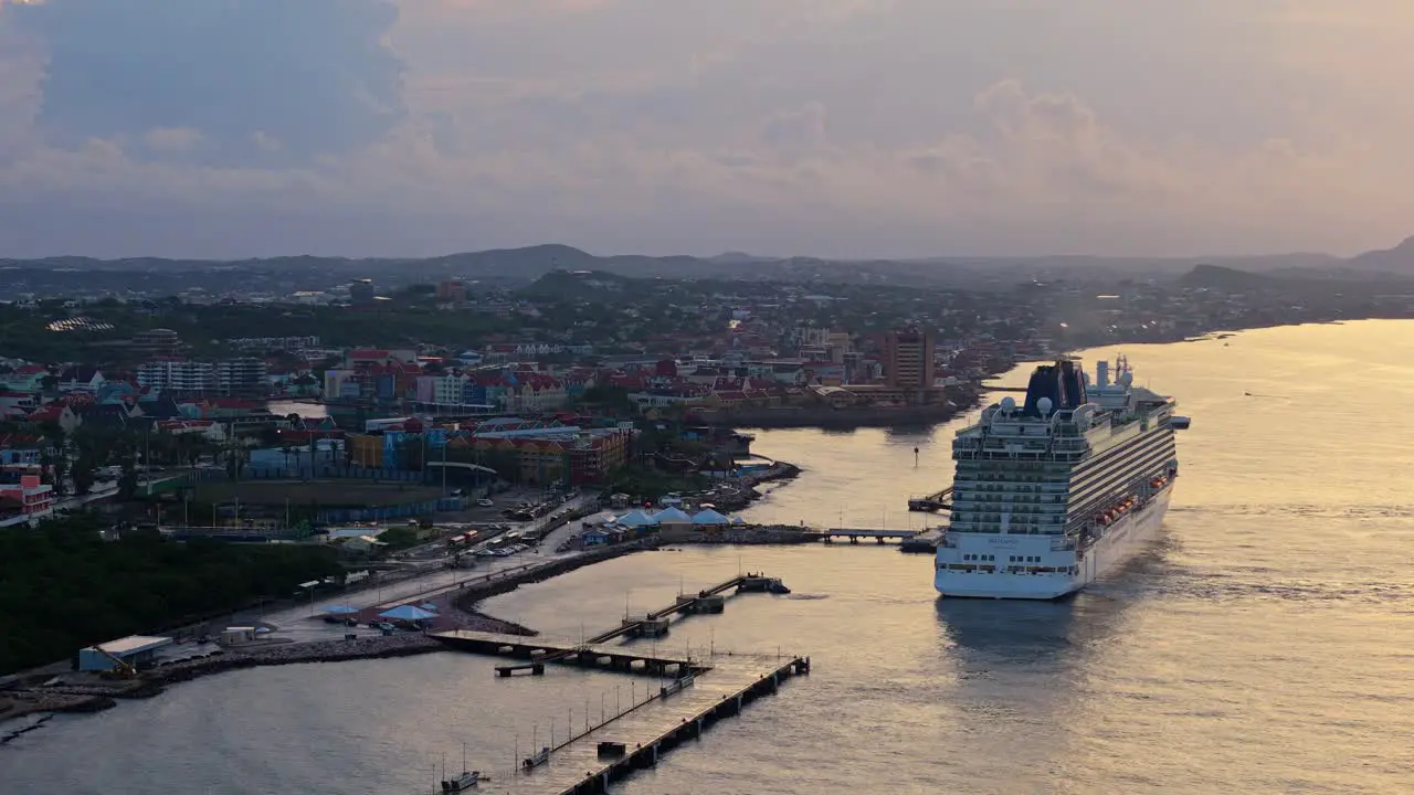 Golden hour light spread across ocean water at cinematic Caribbean port town with cruise ship