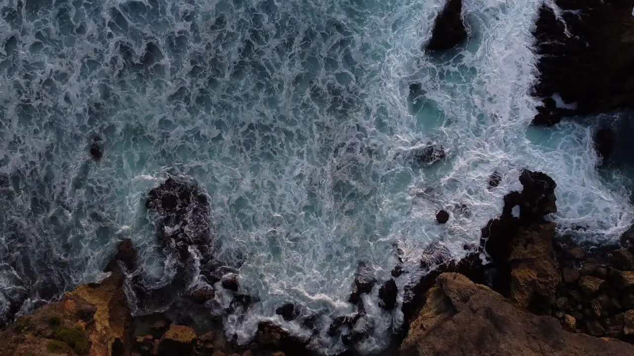 Bird's eye view of the ocean crashing on the shore in Uluwatu Bali