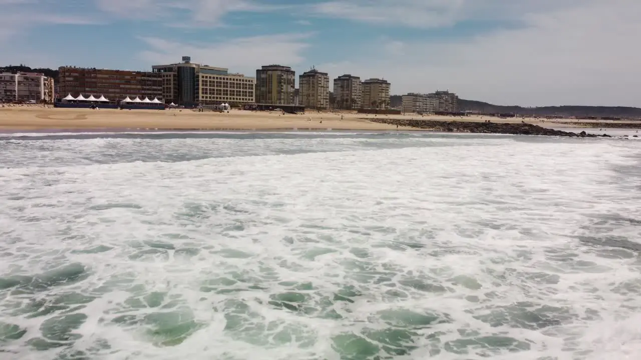 Flyover Ocean waves and seafoam towards to Costa da Caparica Coastline Tilt up shot