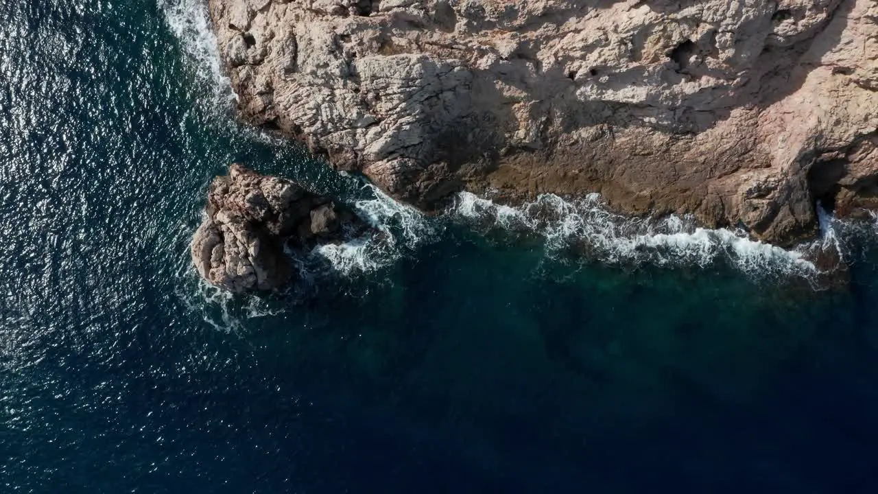 Drone shot waves crashing onto shoreline with seagull passing through the shot