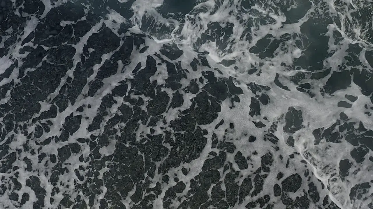 Top down orbit mesmerizing orbit above ocean waves crashing on beach in slow motion