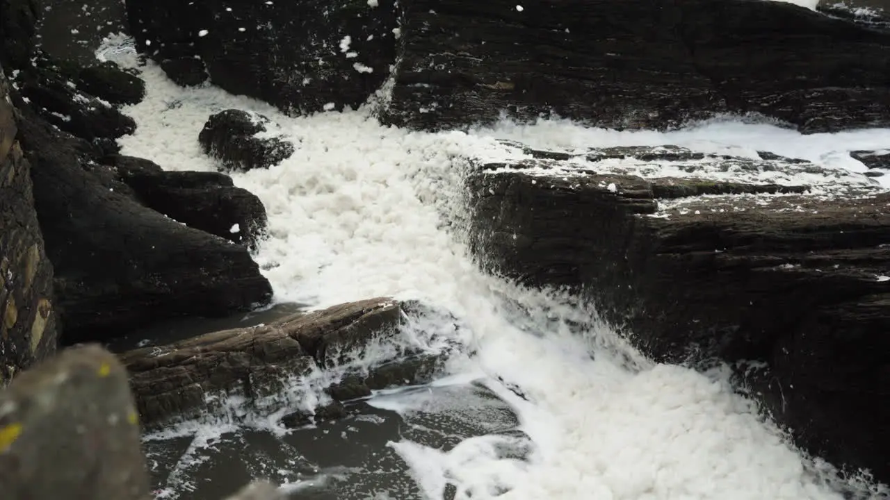 White Sea Foam Washed Ashore And Blown By The Wind Onto The Rocks At Ilfracombe North Devon Coast England United Kingdom