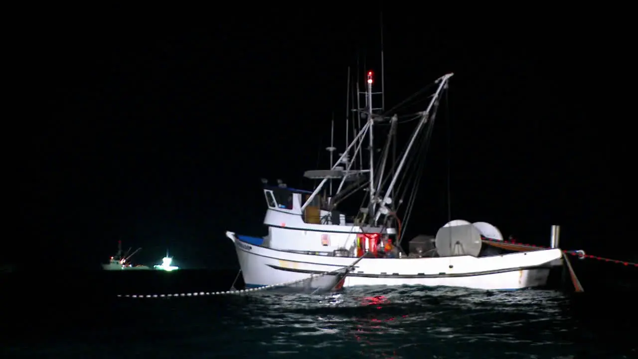 A fishing boat equipped with a net and a winch is working at night