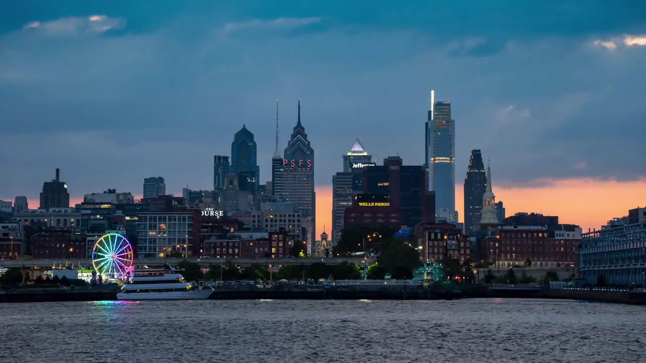 A timelapse view of the skyline of Philadelphia with the sunset behind it and the river in the foreground