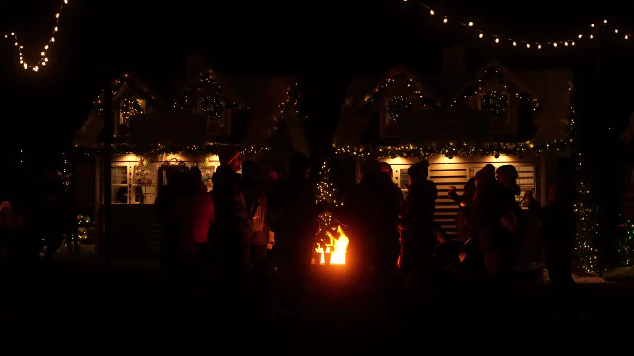 People gather around a firepit at a Christmas holiday festival at nighttime