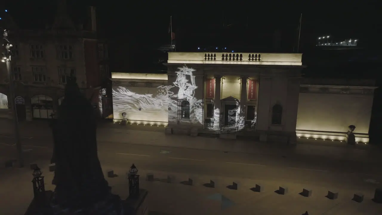 Slow panning by the statue of Queen Victoria located in Hull's Queen Victoria Square continuing into a fly around of the Scrimshaw Gobos projected onto Ferens Art Gallery