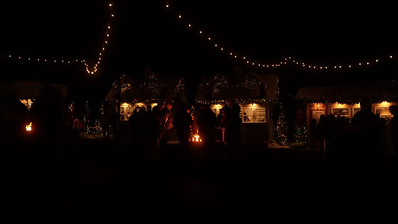 Friends gather around a fire pit at Christmas time to celebrate the holiday at nighttime