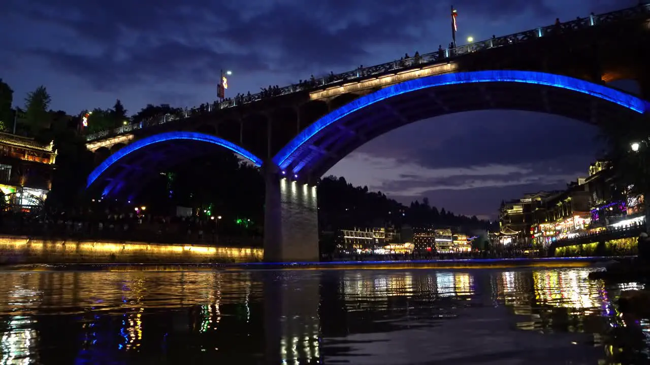 Illuminated at night old historic arched road bridge over Tuo river flowing through the centre of Fenghuang Old Town China