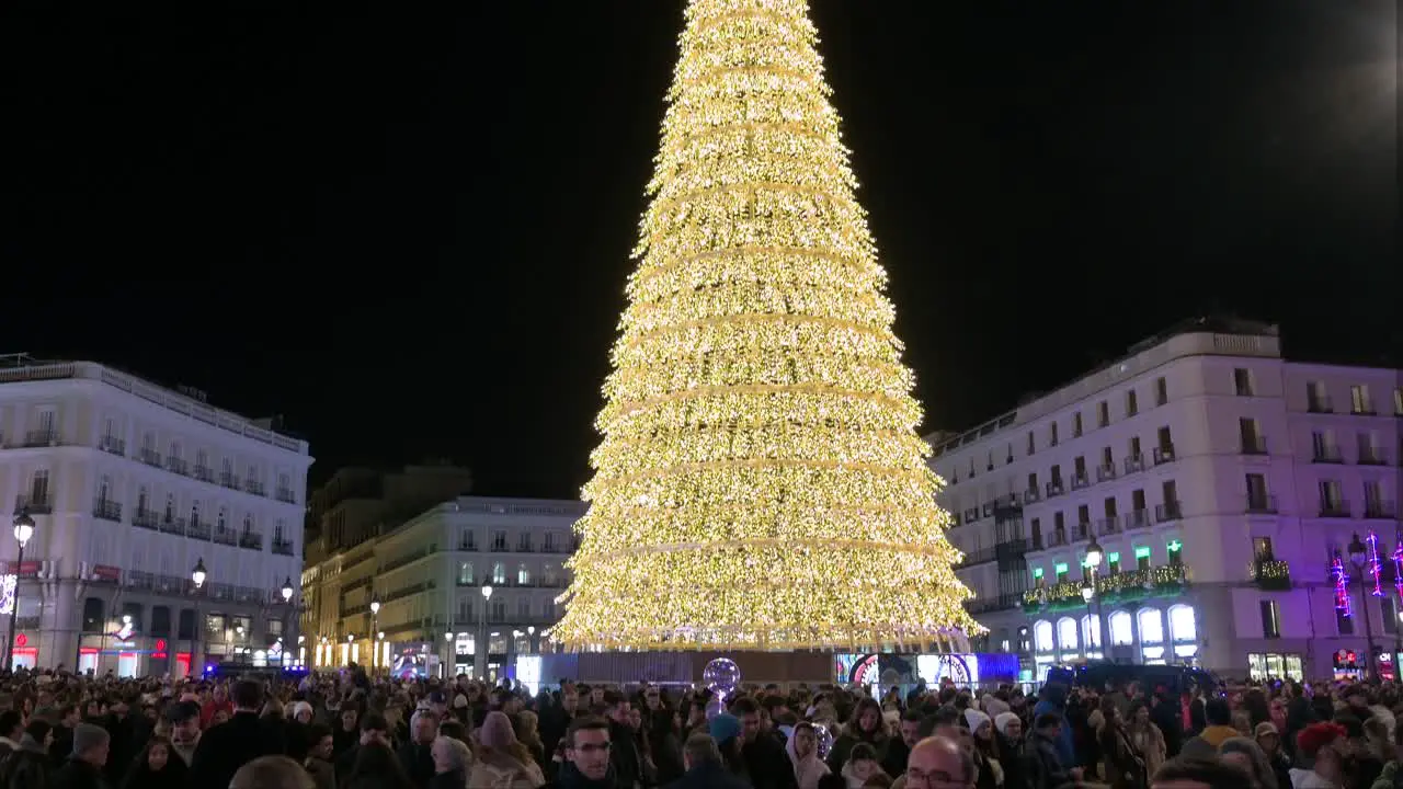 Tilt-down shot of an Illuminated Christmas tree installation decorated with gold LED lights during the Christmas season at Puerta del Sol Square in Madrid