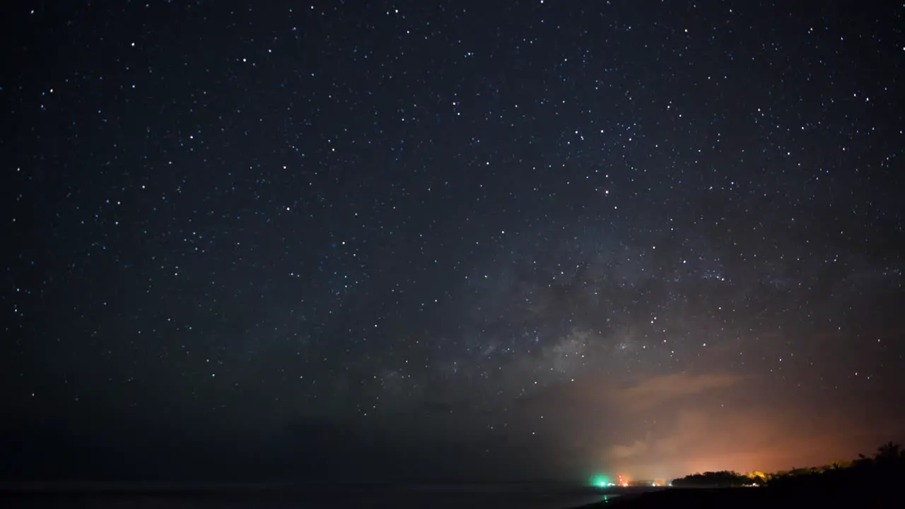 A beautiful Timelapse of the night sky with the milky way getting up on the pacific shore of Costa Rica in march with the city of Cahuita on the bottom