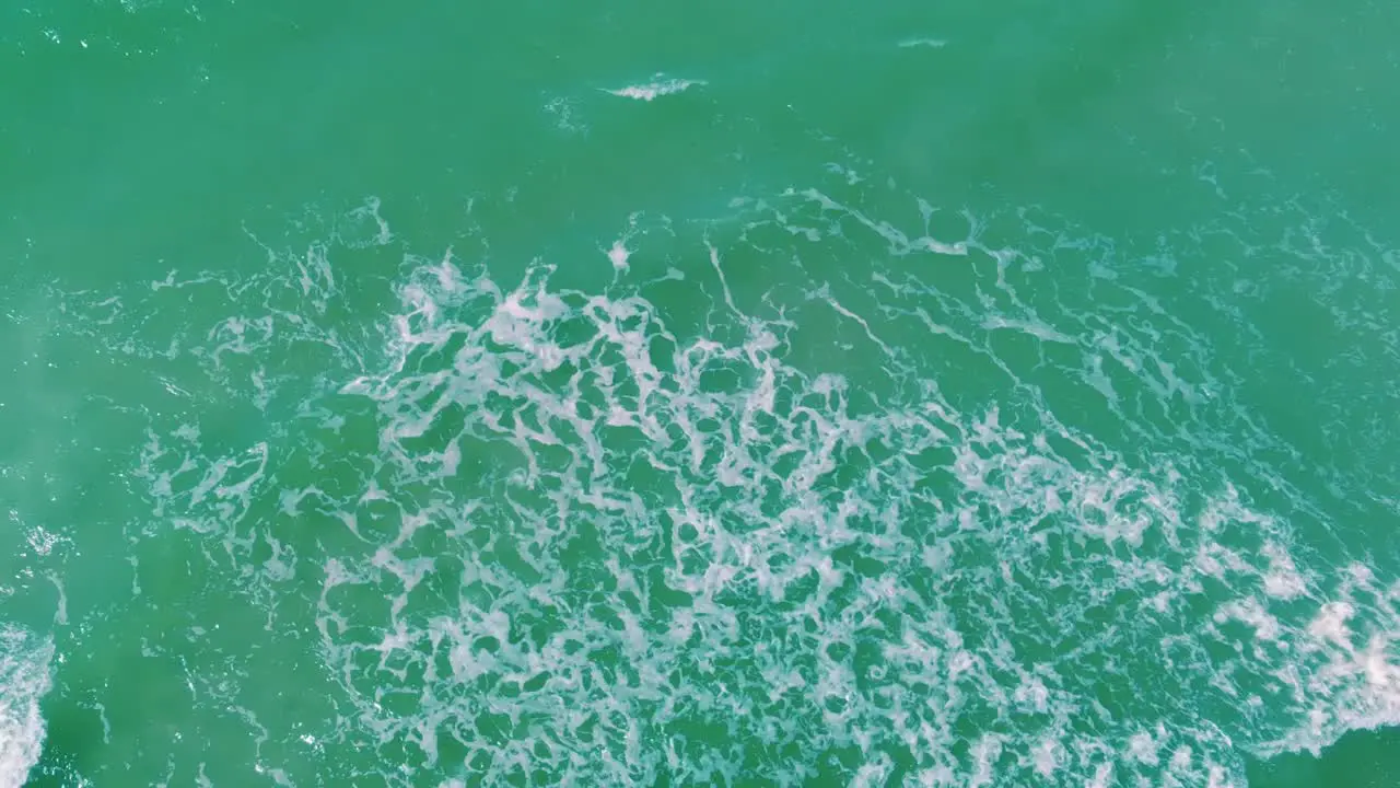 Exotic tropical waves rolling towards ocean shore aerial top down view