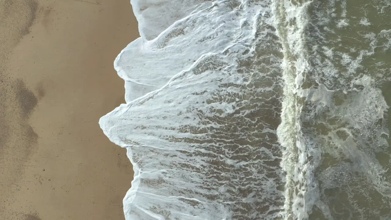 Aerial shot slowly rising of a agitated sea and its powerful waves crashing on the beach